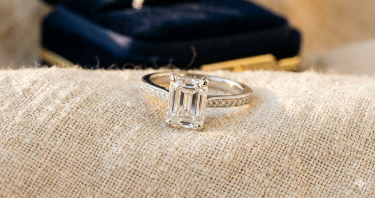 Emerald-cut diamond ring on textured silk in warm golden-hour light.